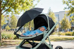 Neonato addormentato nel passeggino all'ombra di un ombrellino parasole orientabile con protezione UV 50+