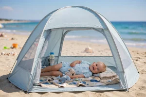 Bambino sdraiato all'ombra di una tenda da spiaggia pop-up con protezione UV 50+ in riva al mare